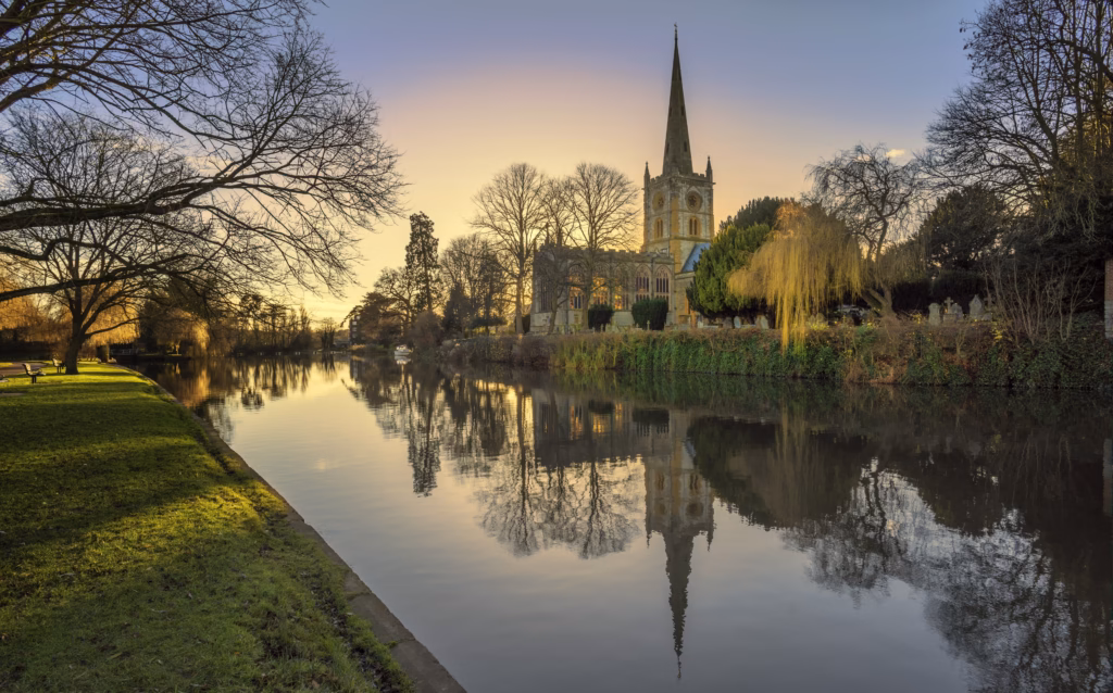 Holy Trinity Church spire reflected in the River Avon at sunset