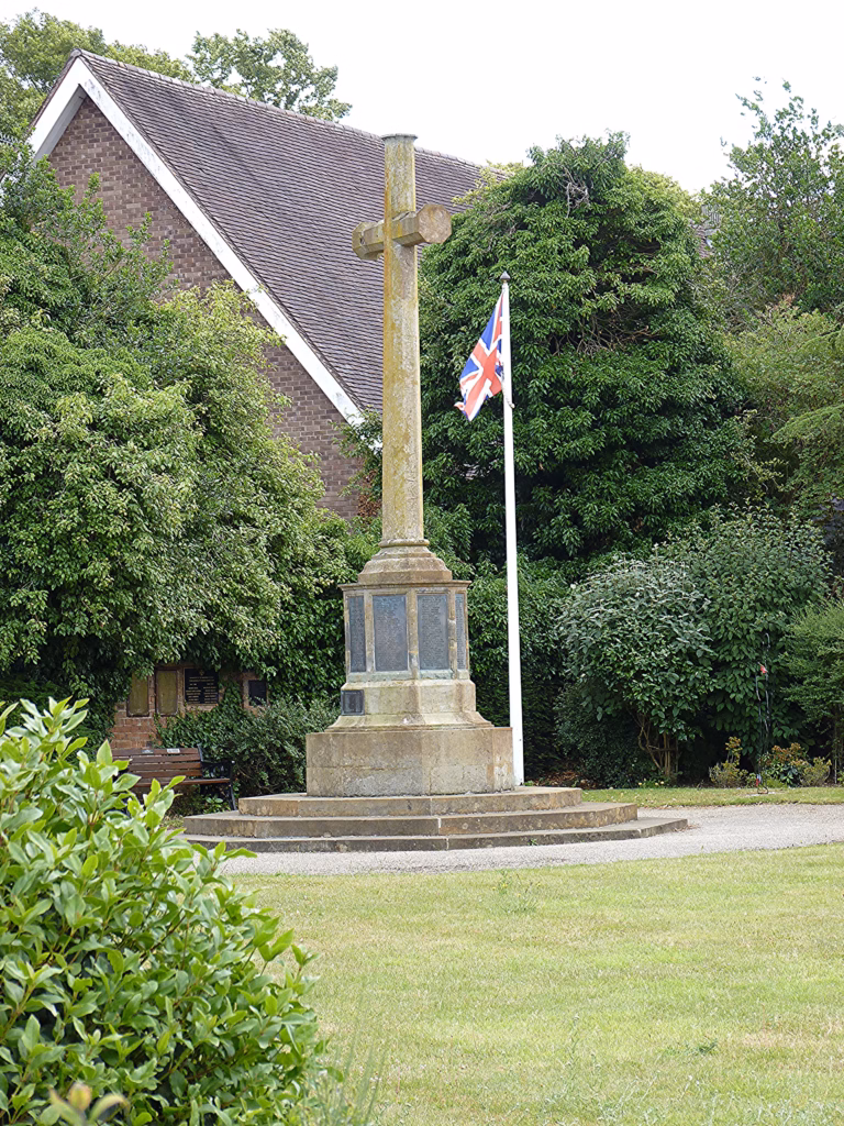 The stone cross war memorial in the Garden of Remembrance, Old Town, Stratford-upon-Avon, with a Union flag